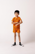 Child wearing an orange outfit with a pattern on a white background
